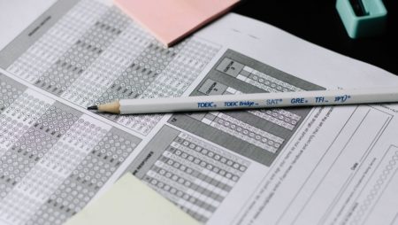 A pencil lying on top of pieces of paper with multiple-choice circles to be filled in.