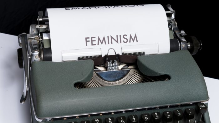 A typewriter with a sheet of paper displaying the text 'FEMINISM'.