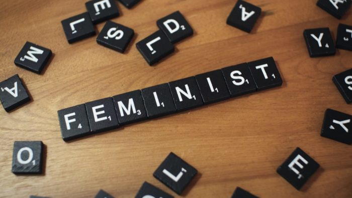 Scrabble tiles showing 'FEMINIST'.