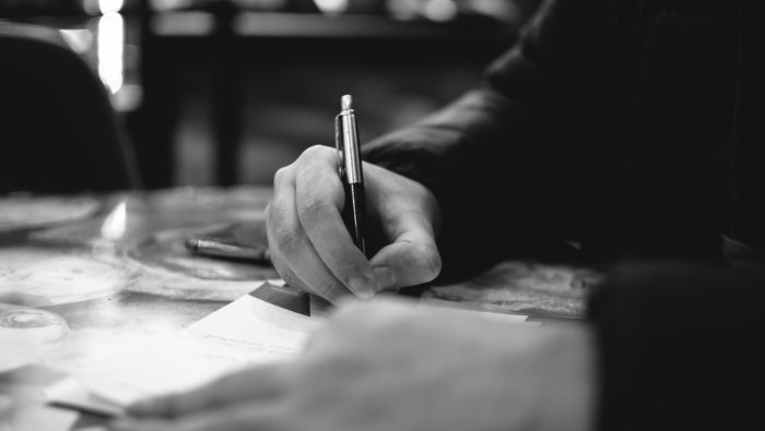 A person using a pen to write text on a piece of paper.