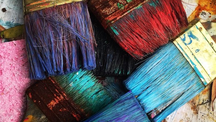 A photograph of paintbrushes with lots of colourful paint