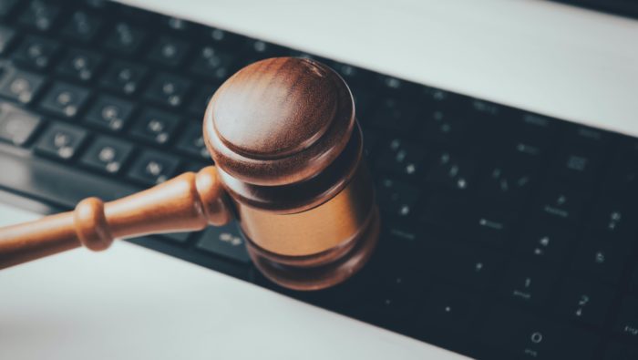 Wooden gavel on top of a Macbook a computer keyboard.