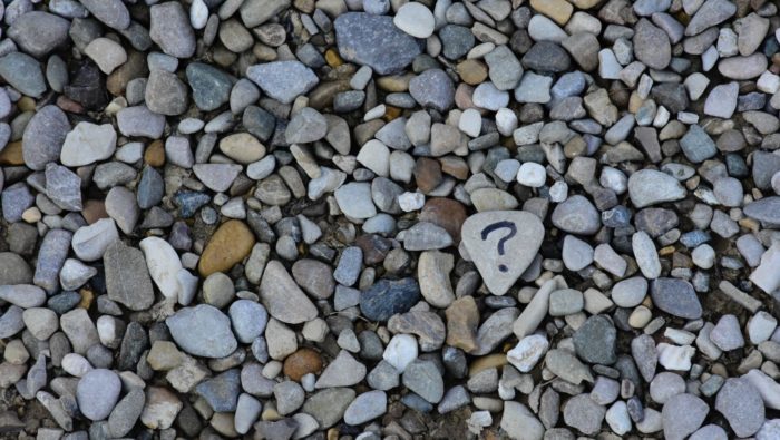 A question mark amongst a sea of rocks and pebbles.