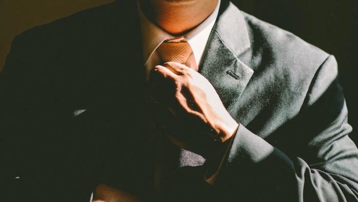 A person wearing a suit and tie and looking officious