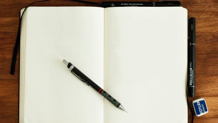 A notebook open to a blank page with a pencil on top and an eraser on the side.