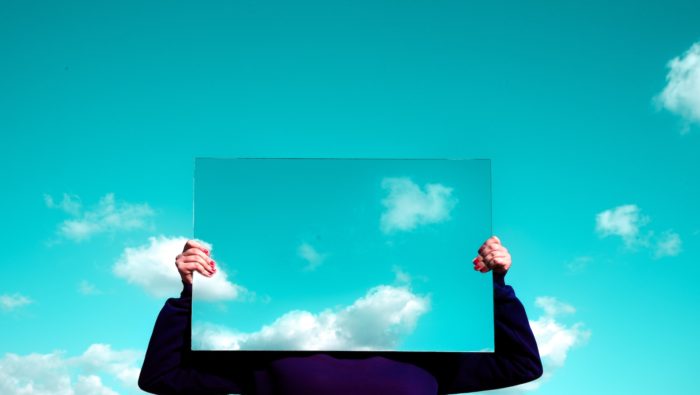 A person holding a mirror reflecting the sky