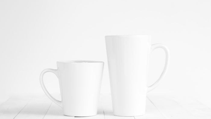 A photo of two white mugs, one short and one tall, against a white background.