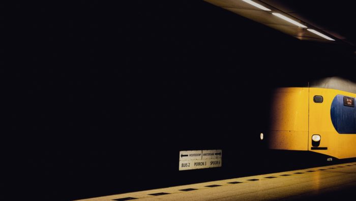 A yellow train car in a dark trainstation