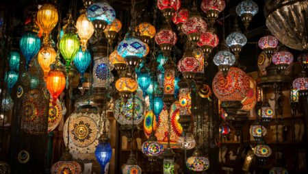 An array of colourful glass lamps hang from a busy market stall
