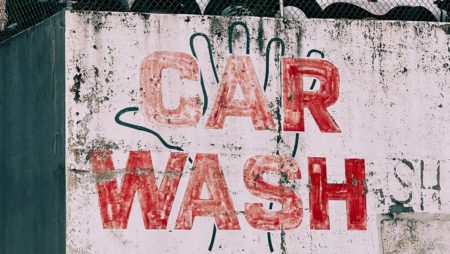 Uma parede coberta de graffiti diz 'Car Wash' em grandes letras vermelhas