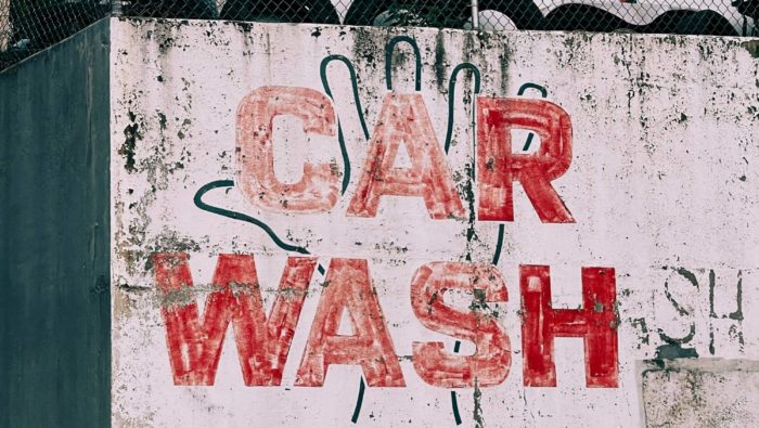 Uma parede coberta de graffiti diz 'Car Wash' em grandes letras vermelhas