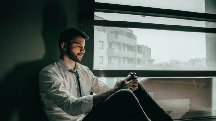 A despondent man scrolls on his mobile phone.