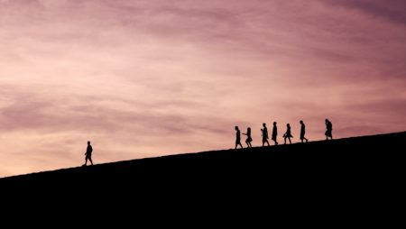 Figures on a mountain skyline follow a lone individual