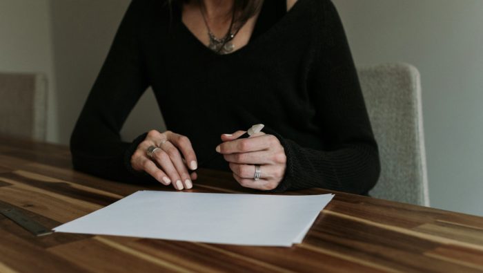 Women sitting at a table with a pen and a white piece of paper