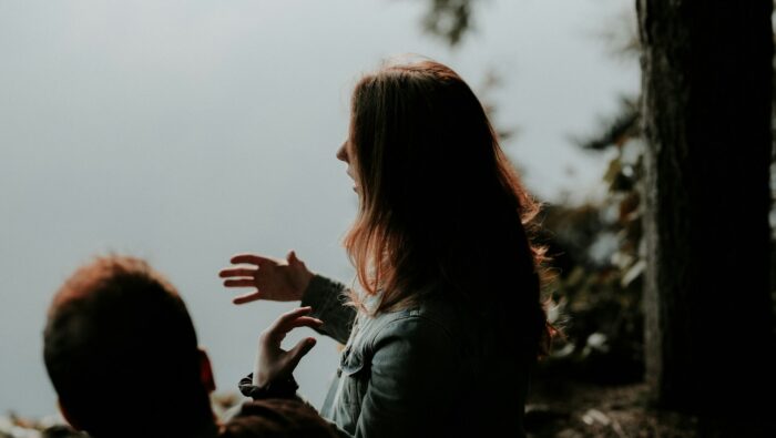 A person talking and gesturing with somebody listening